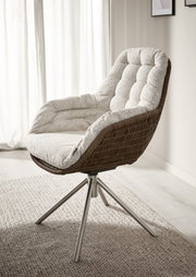 Beige gestoffeerde draaifauteuil met bruin gevlochten rattan kuip en metalen vierpoot, gefotografeerd schuin van voren in een lichte woonkamer