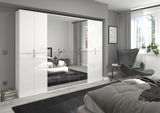 Moderne Garderobenkombination mit weißen Hochglanzfronten und Spiegeln, perspektivisch von der Seite im Schlafzimmer betrachtet.