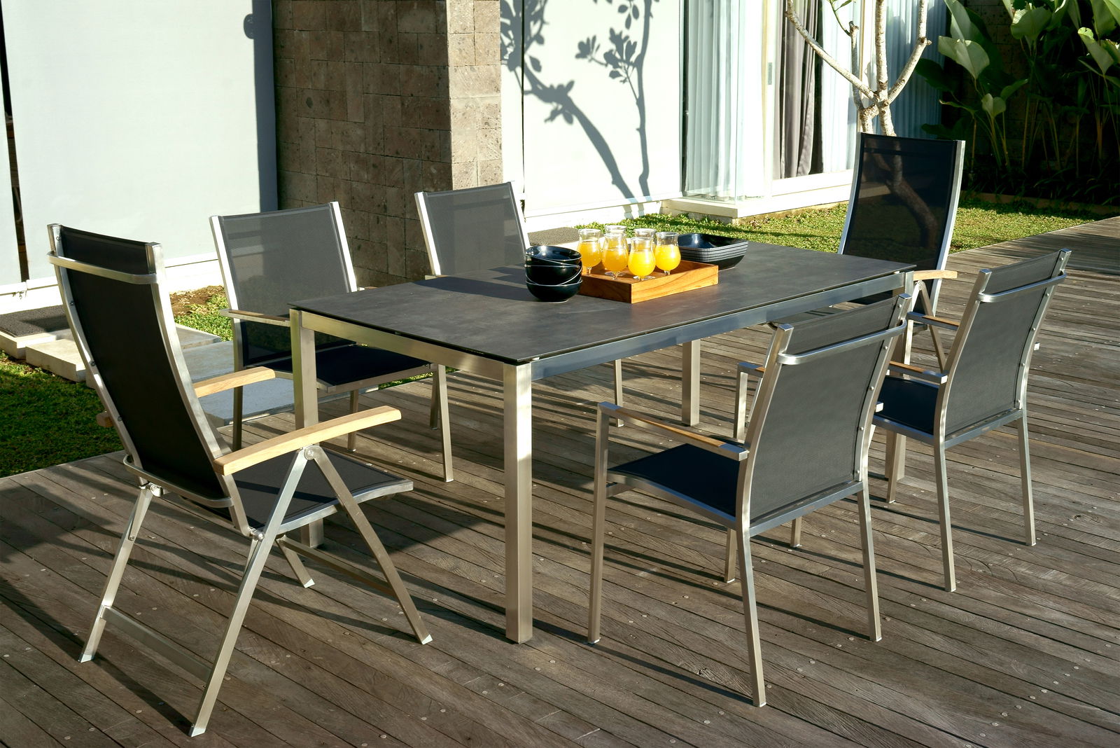 Zebra Stapelsessel ONE Moderner Stapelsessel aus Metall und Textil, auf einer Terrasse um einen Tisch gruppiert, seitliche Perspektive.