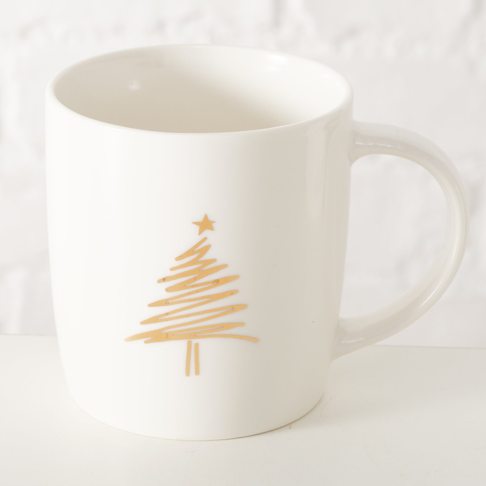 Witte mok met een afbeelding van een gouden kerstboom, gezien vanuit de zijkant