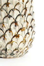 Nahaufnahme eines dekorativen Ornaments mit schuppenartiger Struktur und glänzender Oberfläche in Erdtönen.