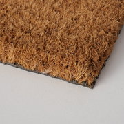 Nahaufnahme einer braunen Fußmatte mit grober Textur, von der Seite fotografiert.