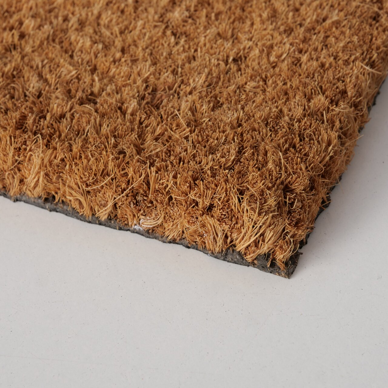 Nahaufnahme einer braunen Fußmatte mit grober Textur, von der Seite fotografiert.