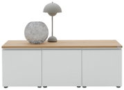 Modernes Sideboard mit weißer Front und heller Holzplatte, darauf eine graue Tischlampe und eine runde Glasvase; Frontalansicht auf weißem Hintergrund.