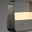 Nahaufnahme einer modernen Tischleuchte mit gebürstetem Metallrahmen und leuchtendem, rechteckigem Lichtpanel.