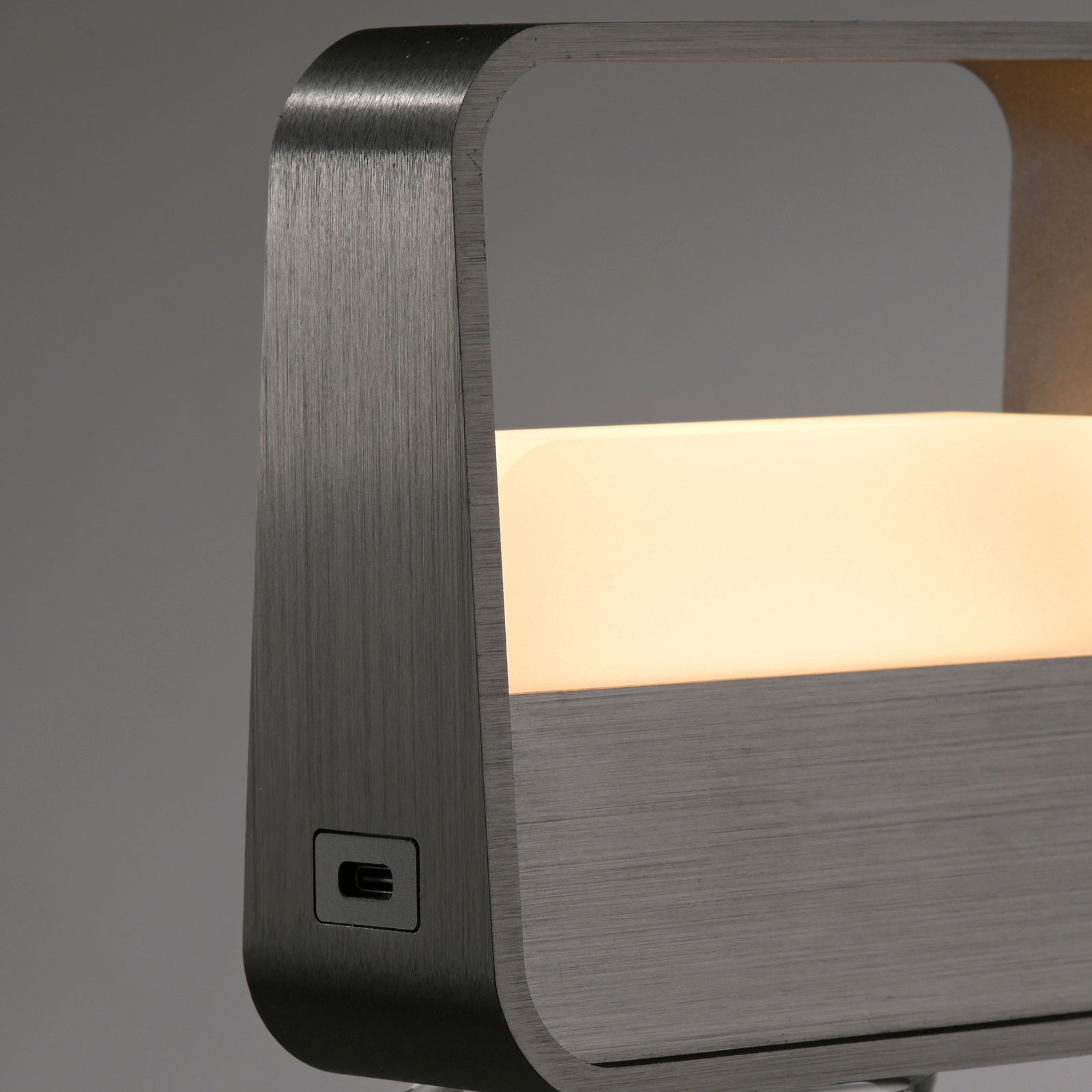 Nahaufnahme einer modernen Tischleuchte mit gebürstetem Metallrahmen und leuchtendem, rechteckigem Lichtpanel.
