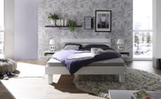 Modernes Schlafzimmer mit einem weißen Holz-Metall-Kopfteil, frontal betrachtet. Das Bett ist mit lila Bettwäsche bezogen und von stilvollen Dekorationen umgeben.