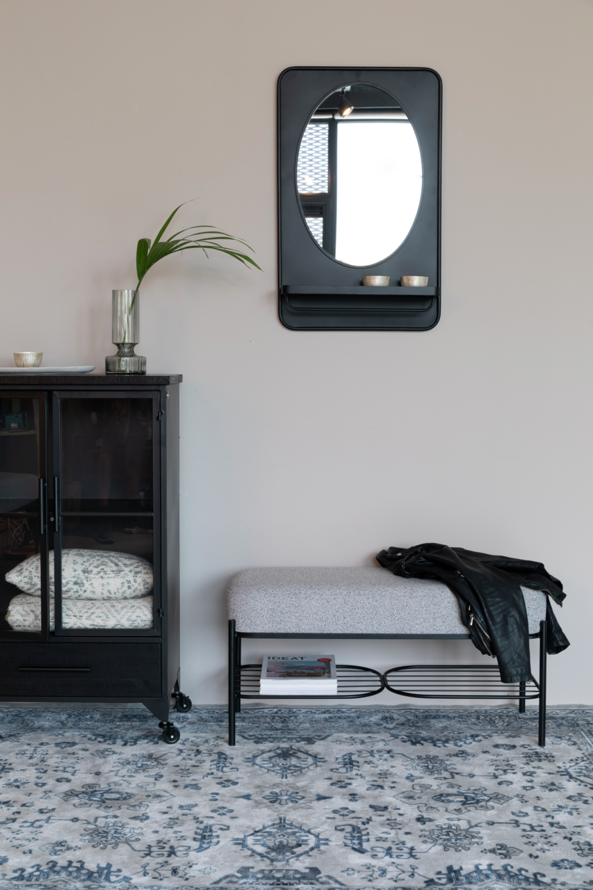 Sitzbank mit grauem Polster und schwarzem Metallgestell, darunter ein Regal mit Zeitschriften, seitliche Perspektive