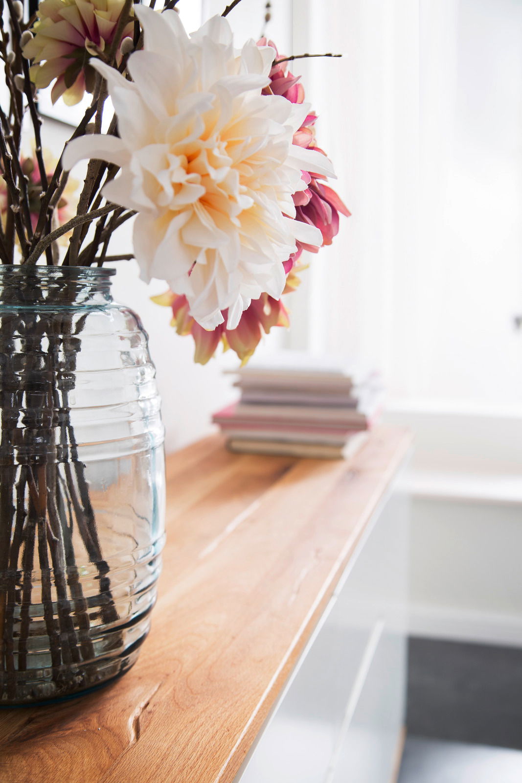 Nahaufnahme eines Holz-Sideboards mit einer Glasvase voller Blumen, seitliche Perspektive.
