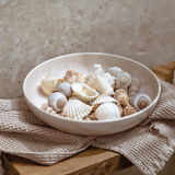 Pastaschale aus Keramik, gefüllt mit Muscheln, auf einem Holzuntergrund mit Stofftuch, seitliche Perspektive