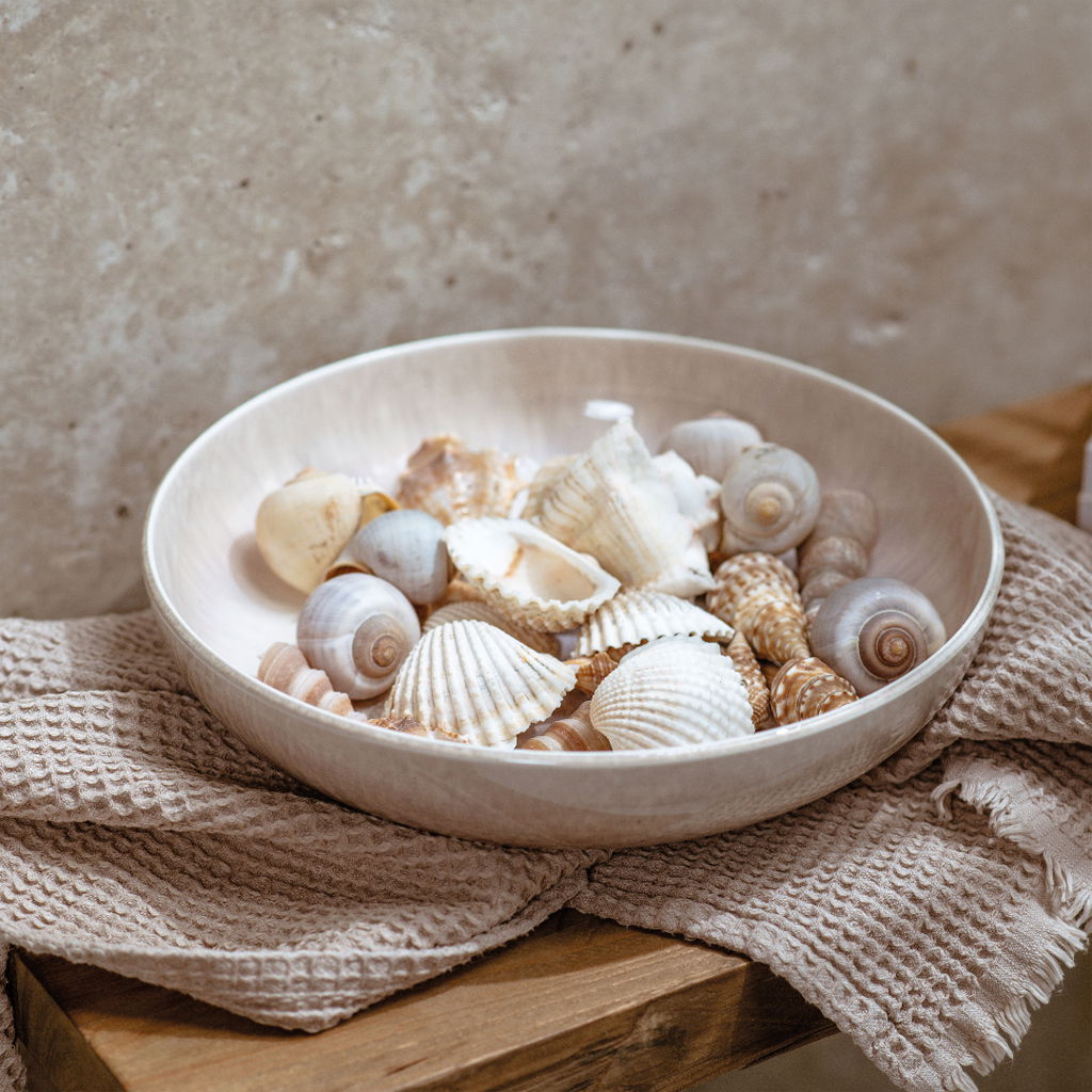 Pastaschale aus Keramik, gefüllt mit Muscheln, auf einem Holzuntergrund mit Stofftuch, seitliche Perspektive