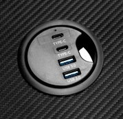 Close-up van een rond aansluitpaneel op een gamingtafel met twee USB 3.0- en twee Type-C-aansluitingen.