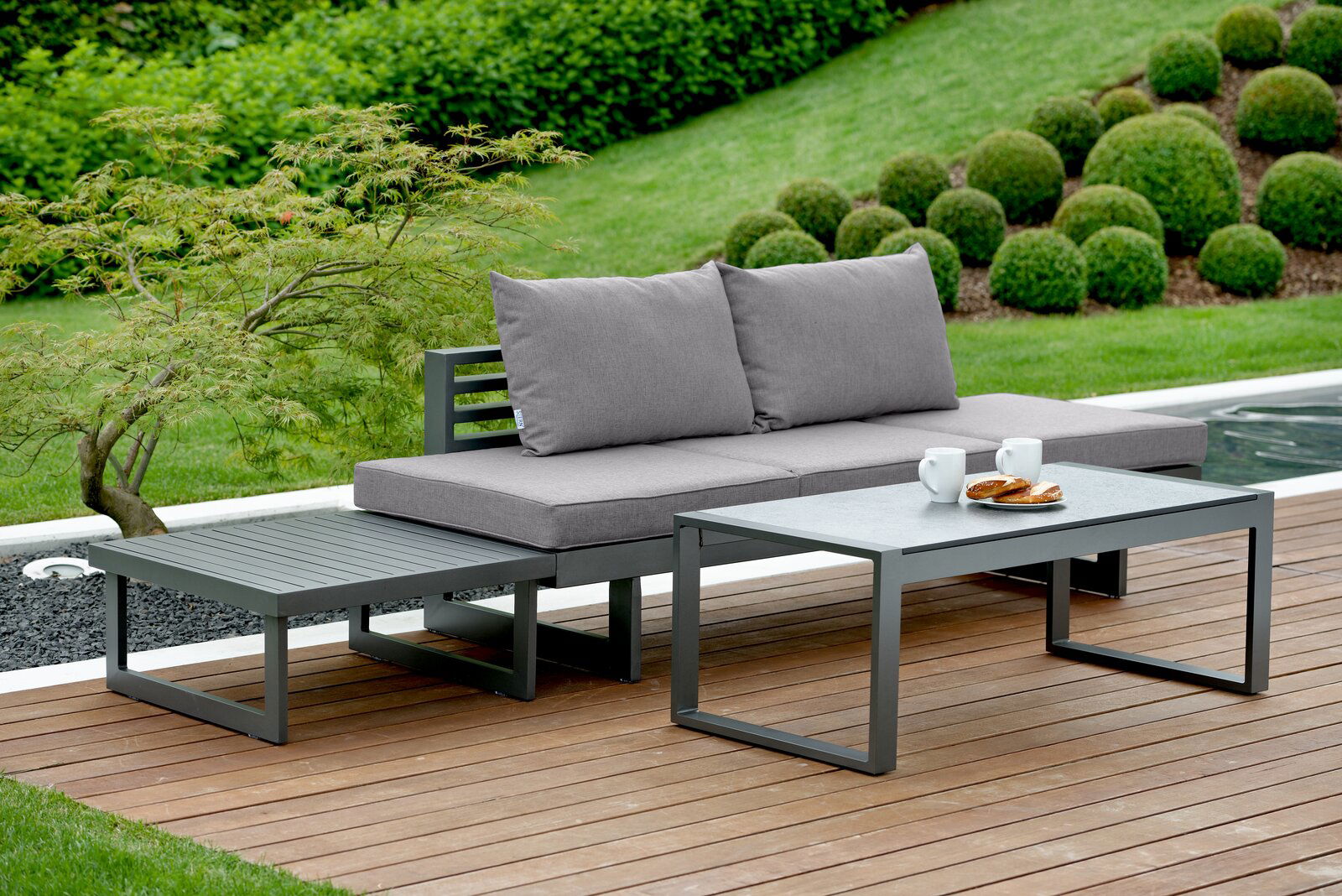 Stern Lounge NEW HOLLY DINING Moderne Lounge-Sitzgruppe im Garten mit grauem Sofa, Couchtisch und Beistelltisch, seitliche Perspektive