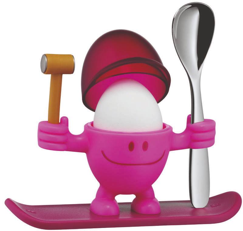 Ein pinker Eierbecher in Form einer fröhlichen Figur mit einem Hammer in der einen Hand und einem Löffel in der anderen, auf einem Ski stehend. Frontalansicht.