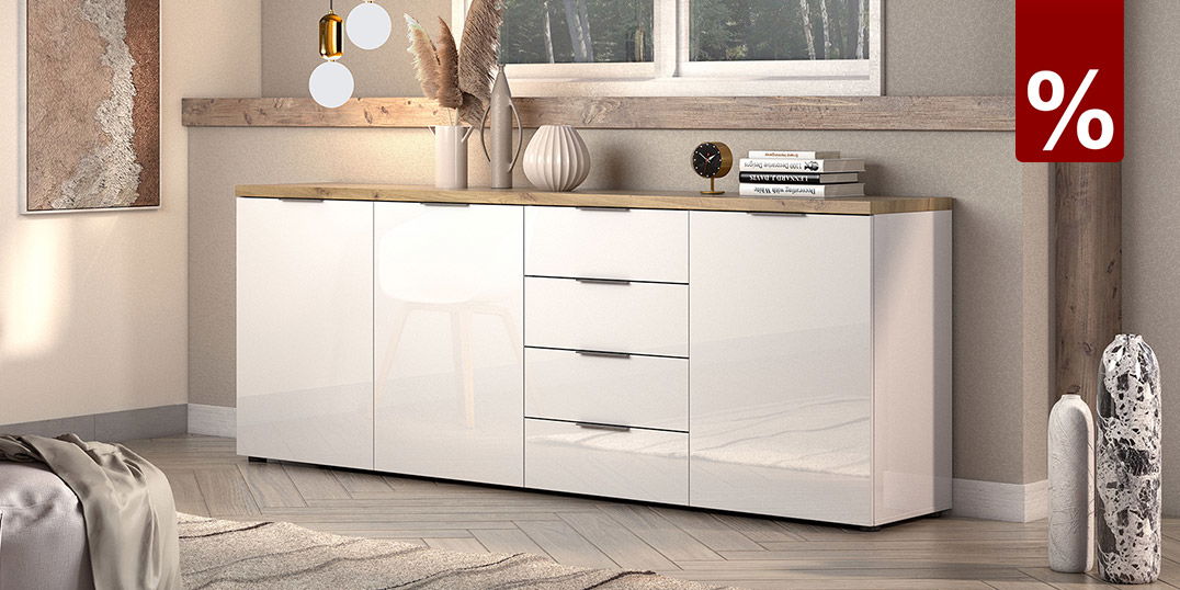 50% Rabatt auf fast alle Kleinmöbel, dahinter steht ein Sideboard. Die Oberfläche ist aus Holz, der Korpus ist hochglanz weiß