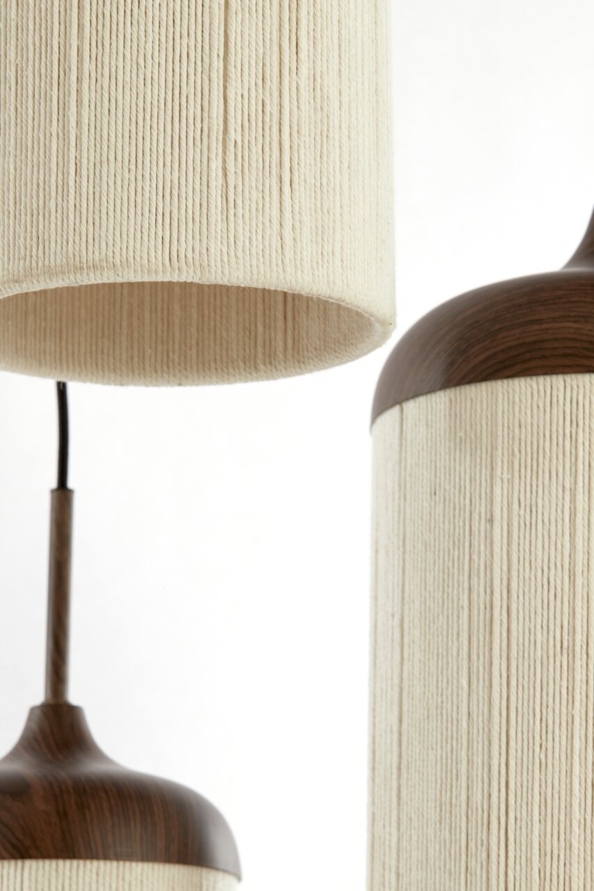 Detailfoto van een moderne hanglamp met een beige, geribbelde stoffen kap en een donkere houten rand, zijaanzicht van dichtbij tegen een witte achtergrond