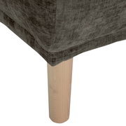 Nahaufnahme eines Hockers mit grauem Stoffbezug und hellem Holzbein, Perspektive von unten.