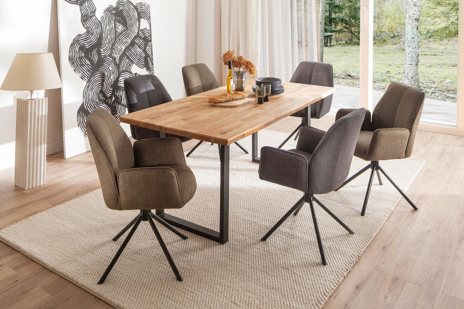 Moderner Esstisch mit Holzplatte und schwarzen Metallbeinen, umgeben von sechs gepolsterten Stühlen in einem hellen Esszimmer mit Blick auf den Garten.