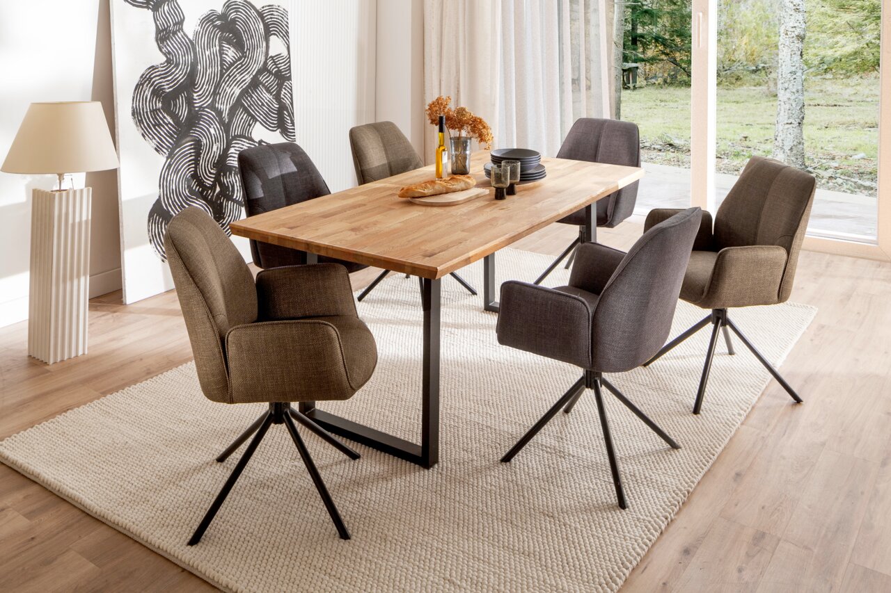 Moderner Esstisch mit Holzplatte und schwarzen Metallbeinen, umgeben von sechs gepolsterten Stühlen in einem hellen Esszimmer mit Blick auf den Garten.