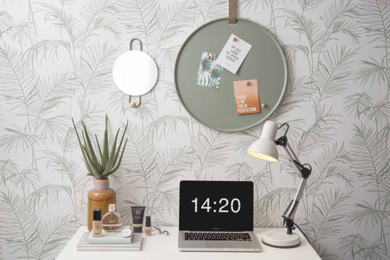 Een rond, groen memobord aan de muur met notities en kaartjes, met daarnaast een spiegel. Perspectief: vooraanzicht op het memobord in een stijlvol ingerichte kamer.
