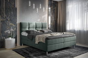 Boxbett in modernem Schlafzimmer, seitliche Perspektive, mit grauem Polsterkopfteil und eleganter Beleuchtung.