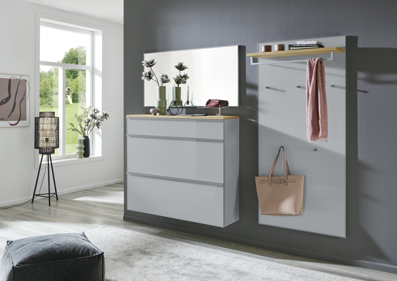 Modernes Garderoben-Set in Grau mit Holzablage, bestehend aus Kommode mit Spiegel und Wandpaneel mit Haken und Ablage, in einem hellen Flur – Frontansicht in leichter Schrägperspektive von links.