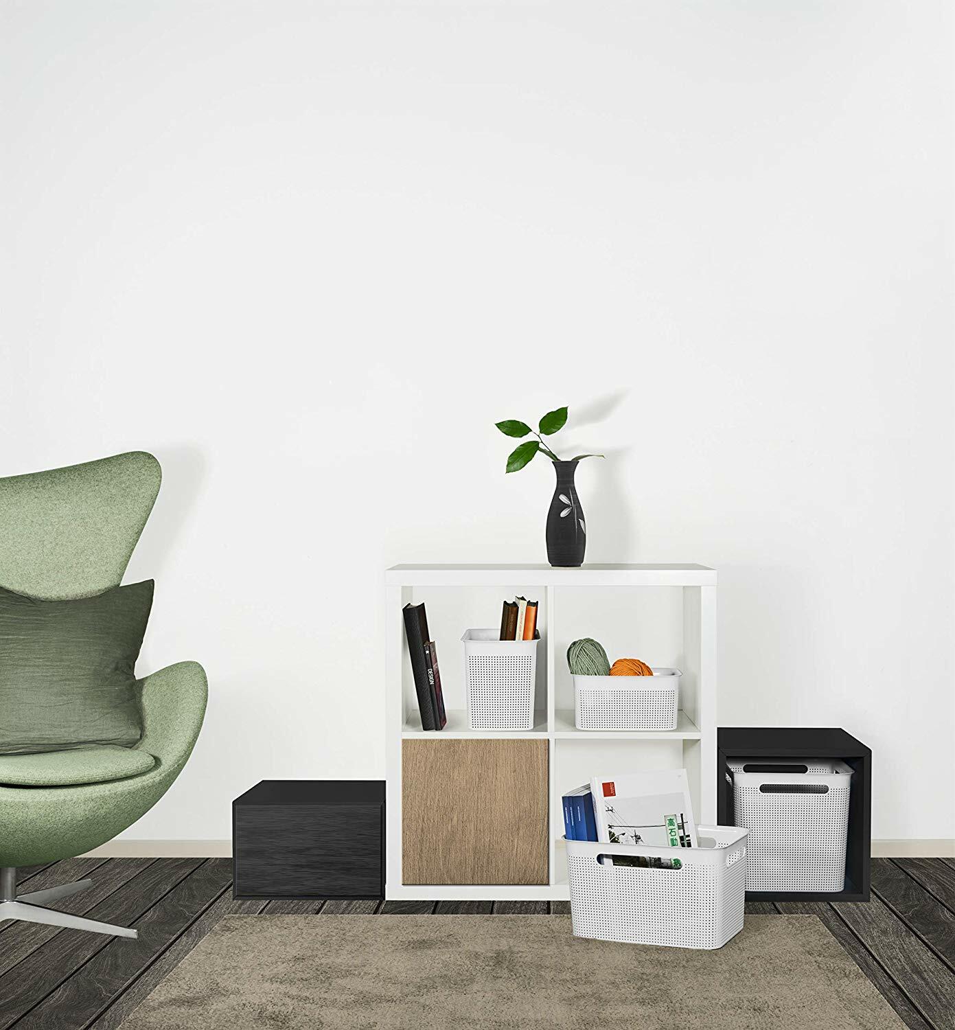 Quadratische Aufbewahrungsboxen in einem modernen Wohnzimmer, frontal fotografiert, in einem weißen Regal platziert.