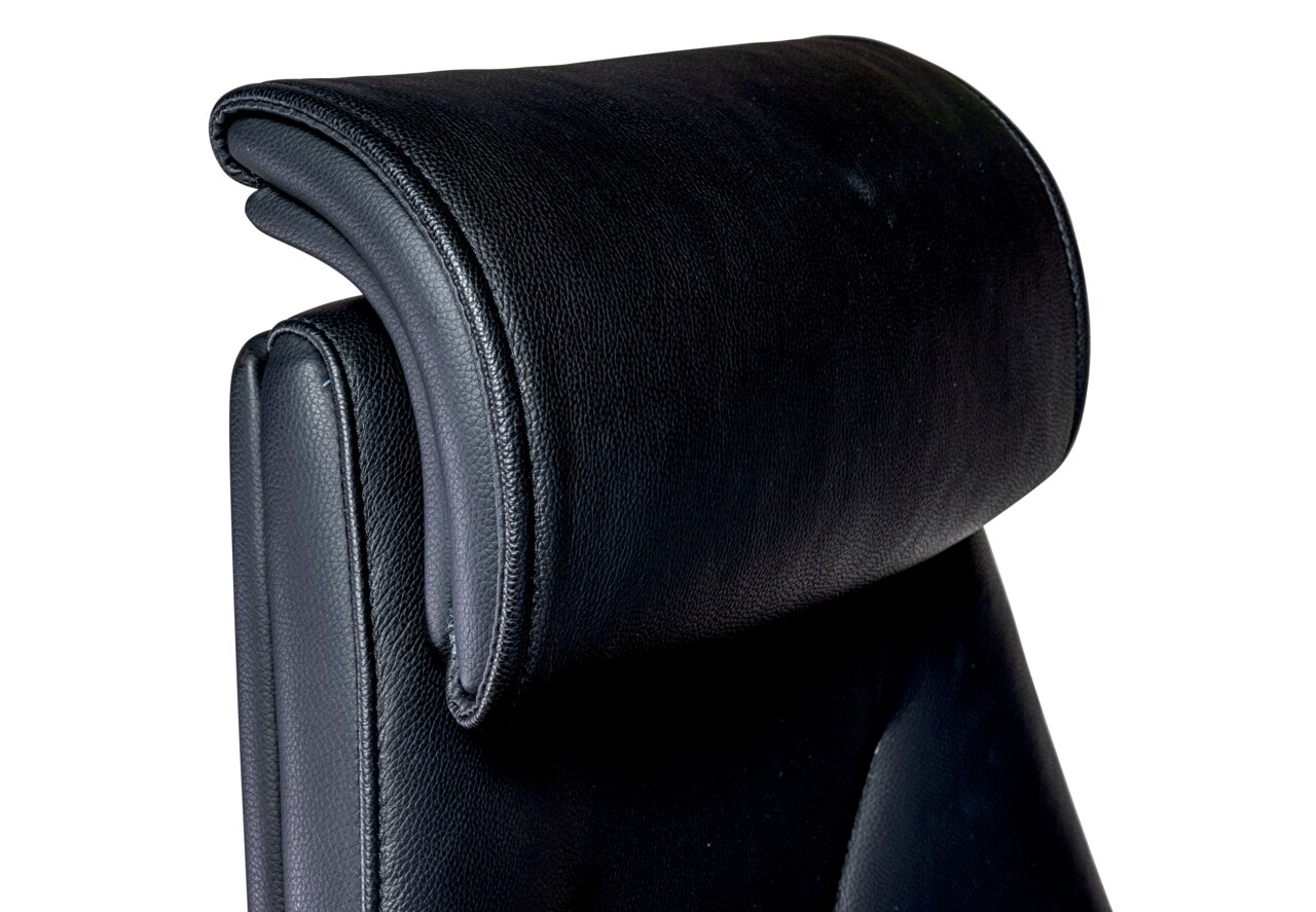 Nahaufnahme der Kopfstütze eines schwarzen Chefsessels aus Leder, seitliche Perspektive