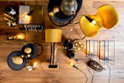 Vogelperspektive auf einen stilvoll dekorierten Raum mit einem Beistelltisch, auf dem goldene Dekorationen und Kerzen stehen, umgeben von einer gelben Lampe, einem gelben Stuhl und weiteren dekorativen Elementen auf einem Holzboden.