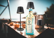 Akku-Tischleuchte VANNIE 3 in stilvollem Design, präsentiert in einer sommerlichen Outdoor-Umgebung mit direkter Frontalansicht.