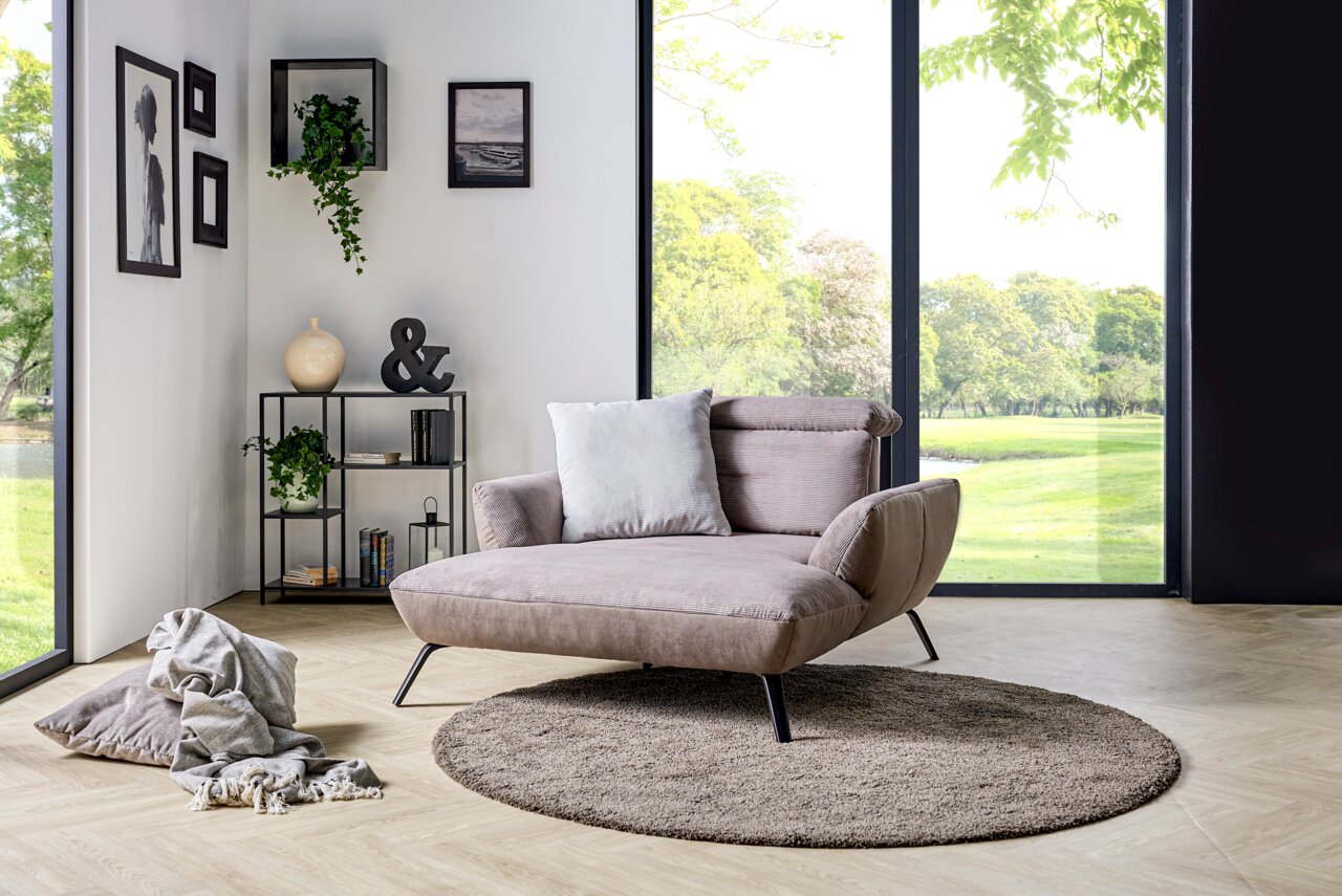 Modernes Loveseat in einem hellen Raum mit großen Fenstern, seitliche Perspektive