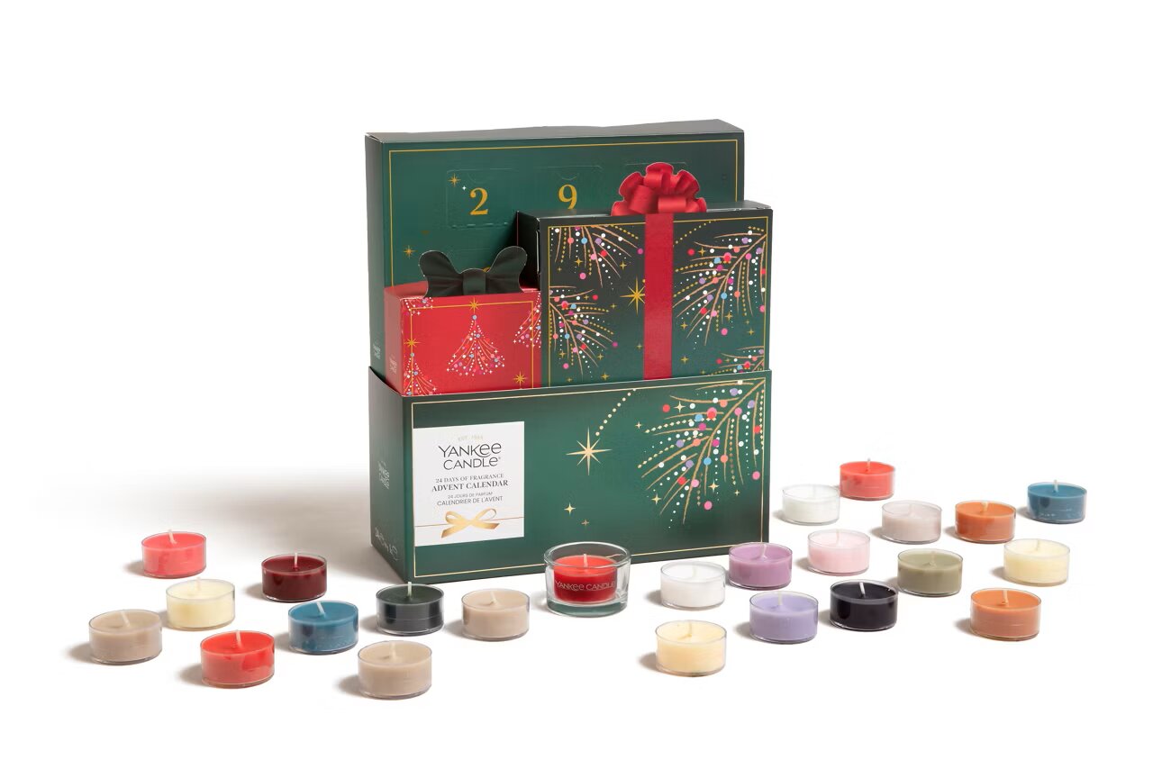 Yankee Candle adventskalender in donkergroene geschenkverpakking met feestelijk vuurwerkdesign, omringd door 24 kleurrijke geurkaarsjes, schuin van voren gezien