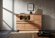Modernes Highboard aus Holz mit dekorativen Elementen, frontal fotografiert. Es hat eine Glasvitrine und ist von natürlichem Licht beleuchtet.