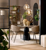 Eleganter Essbereich mit rundem Tisch und zwei gepolsterten Stühlen, dekoriert mit modernen Vasen und hängenden Glaskugelleuchten, seitliche Perspektive.