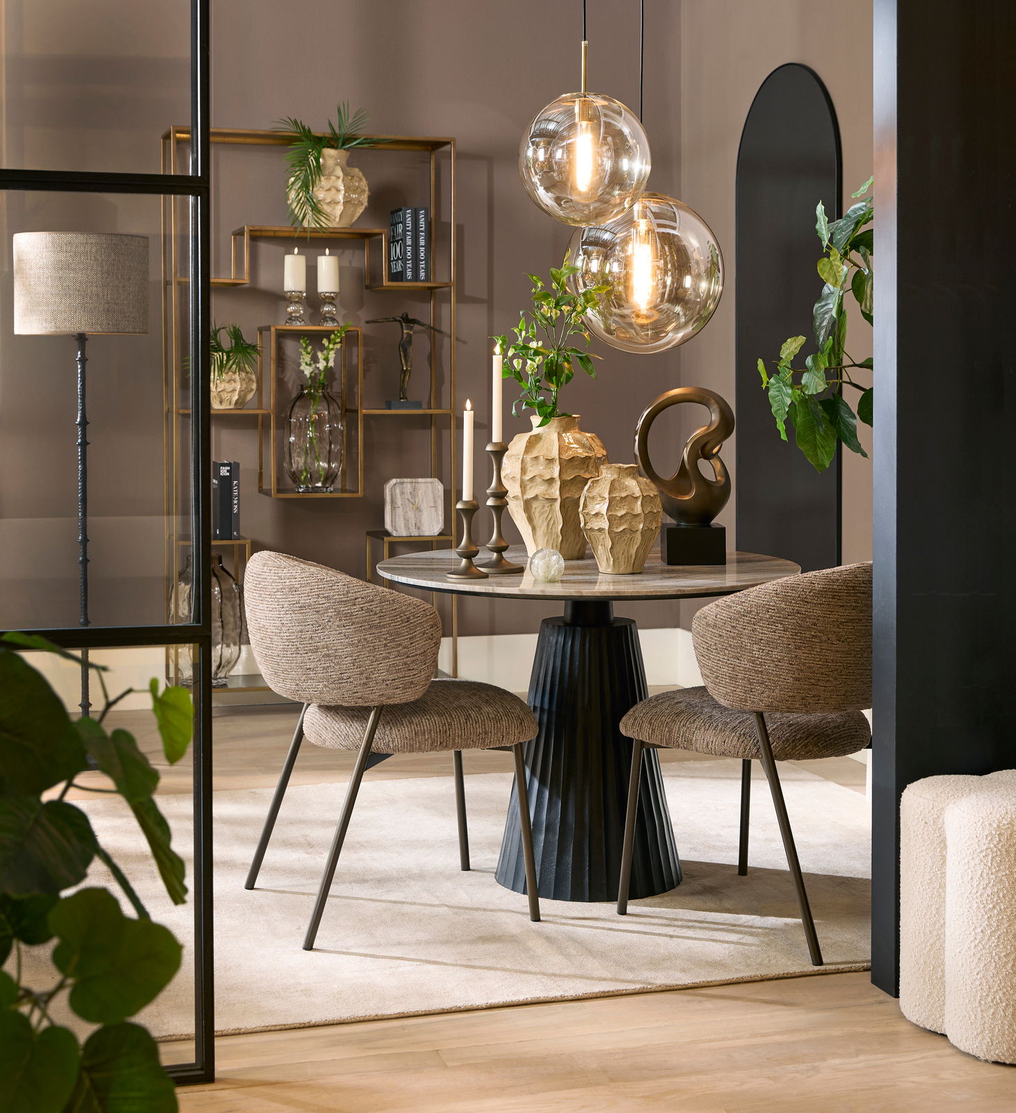 Eleganter Essbereich mit rundem Tisch und zwei gepolsterten Stühlen, dekoriert mit modernen Vasen und hängenden Glaskugelleuchten, seitliche Perspektive.