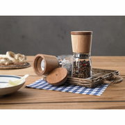 Twee kruidenmolens van hout en glas op een tafel, één staand en één liggend, gevuld met een mengsel van peperkorrels en zout. Aanzicht van voren.