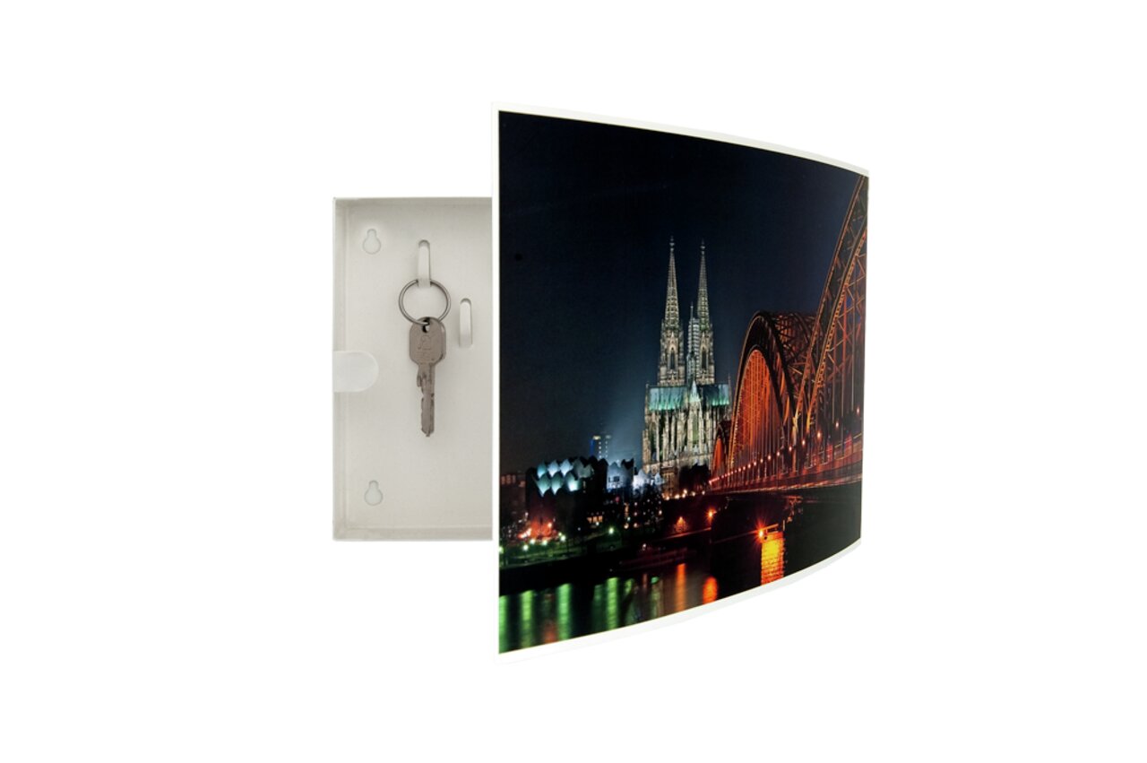 Schlüsselkasten mit geöffnetem Türchen, das ein Bild des Kölner Doms und der Hohenzollernbrücke bei Nacht zeigt, mit einem Schlüssel im Inneren. Perspektive von vorne links.
