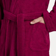 Nahaufnahme eines weinroten Bademantels mit Schalkragen, der eine Hand in der Tasche zeigt.