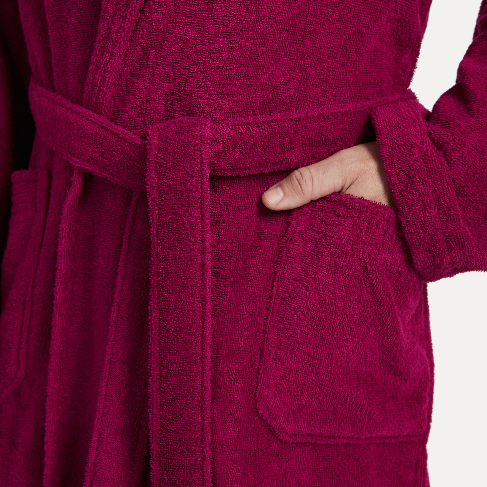 Nahaufnahme eines weinroten Bademantels mit Schalkragen, der eine Hand in der Tasche zeigt.