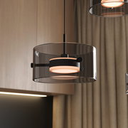 Moderne LED-Hängeleuchte mit transparentem Glaszylinder und schwarzem Metallrahmen, seitliche Perspektive