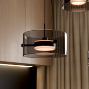 Moderne LED-Hängeleuchte mit transparentem Glaszylinder und schwarzem Metallrahmen, seitliche Perspektive