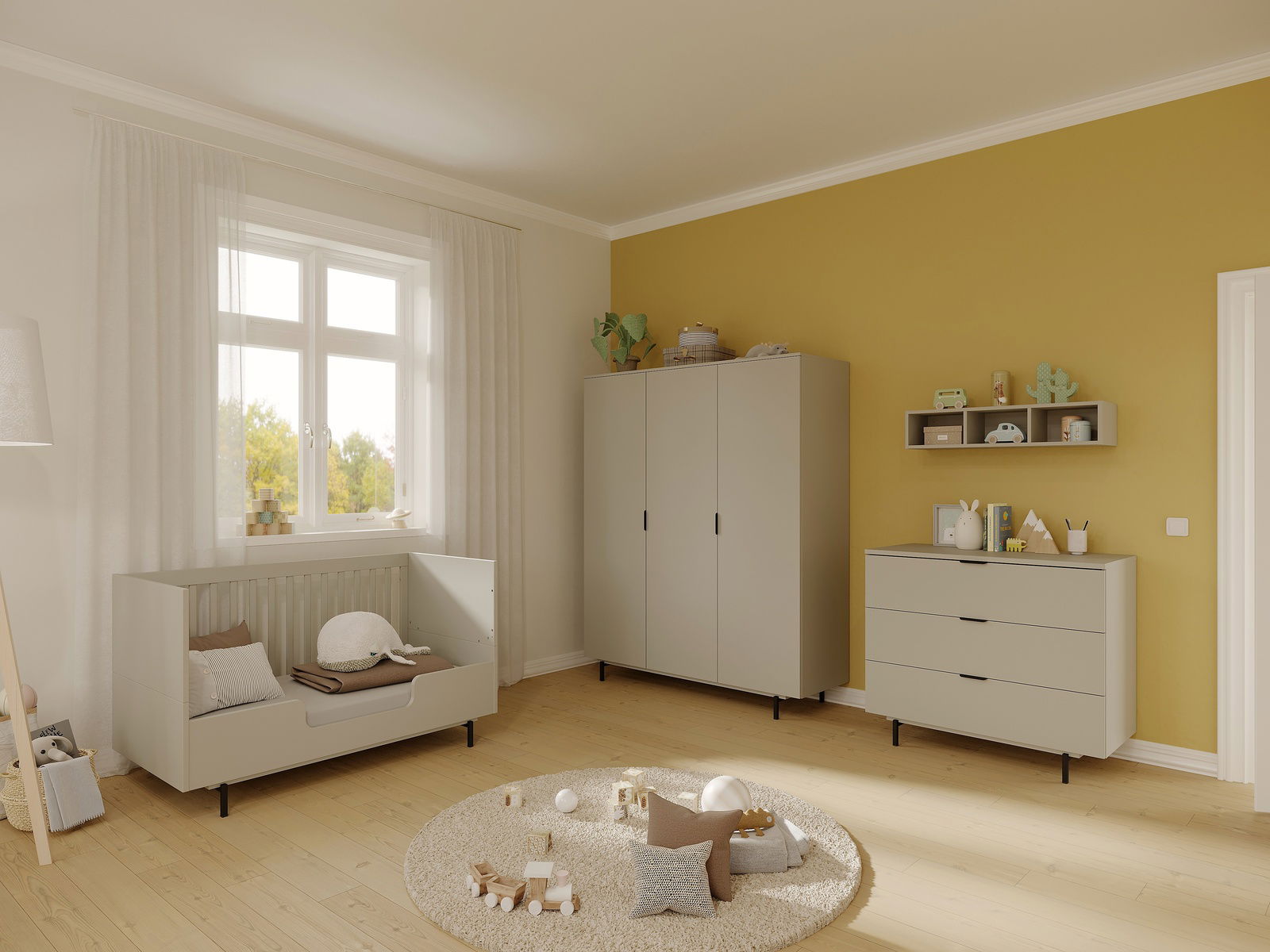 Kinderzimmer mit gelber Wand, bestehend aus einem grauen Gitterbett, einem Kleiderschrank und einer Kommode, aus der Perspektive von links betrachtet.