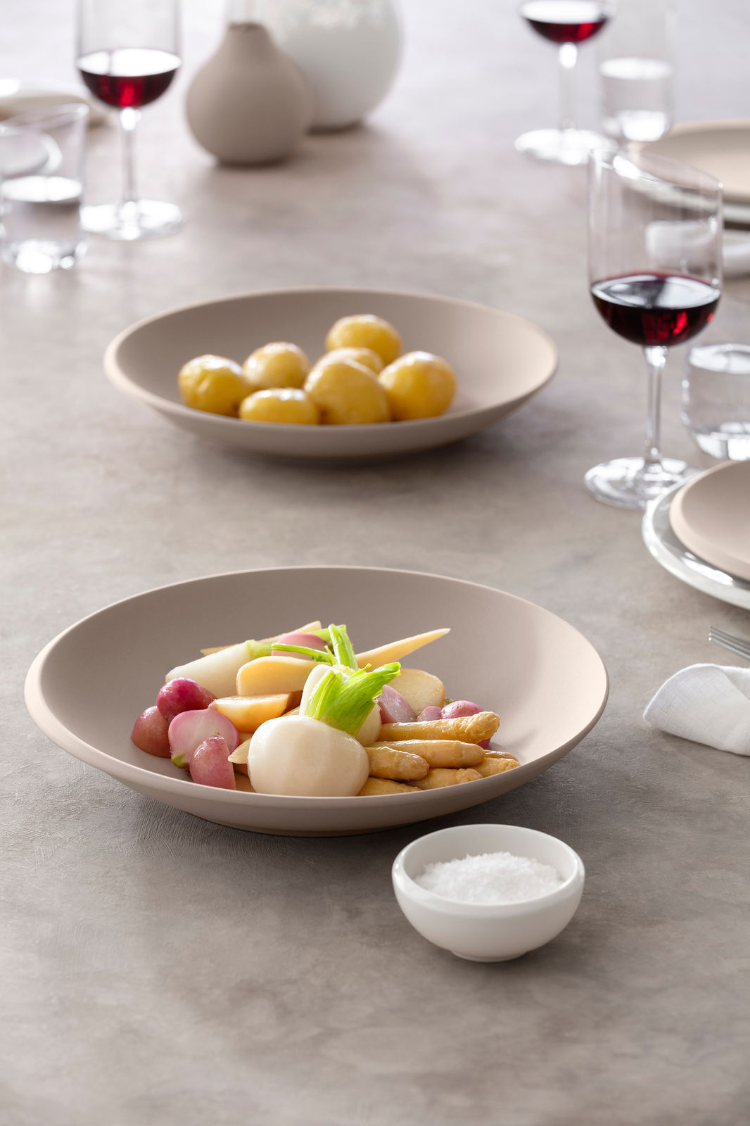 Beige Schale NewMoon 320ml mit Gemüse, seitliche Perspektive, gedeckter Tisch mit Weingläsern im Hintergrund
