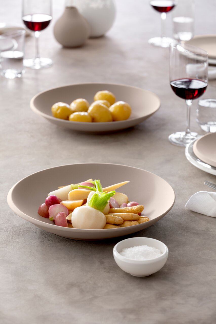 Villeroy & Boch Schale NewMoon 320ml beige NEW MOON Beige Schale NewMoon 320ml mit Gemüse, seitliche Perspektive, gedeckter Tisch mit Weingläsern im Hintergrund