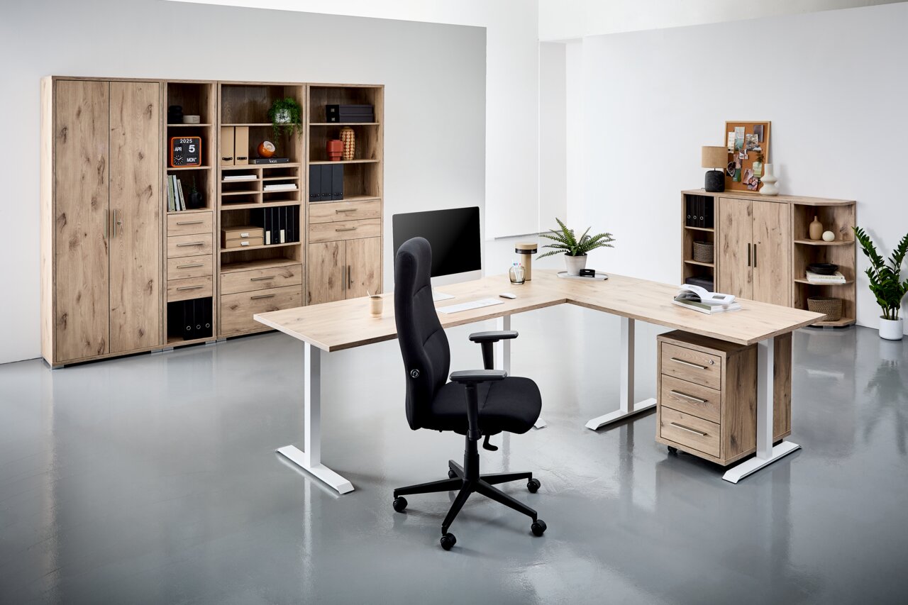 Voleo Schubladen-Set CONNECT Moderne Büromöbel in einem hellen Raum, bestehend aus einem L-förmigen Schreibtisch mit Holzoberfläche, einem schwarzen Bürostuhl und mehreren Regalen und Schränken aus Holz. Perspektive von vorne.