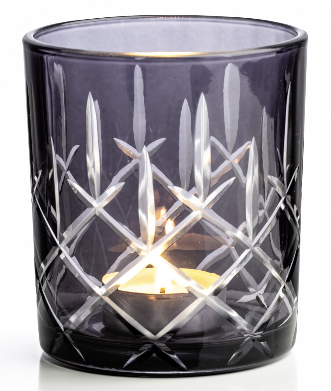 Graues Windlicht mit Schliffmuster, seitliche Perspektive, beleuchtet von einer Kerze.