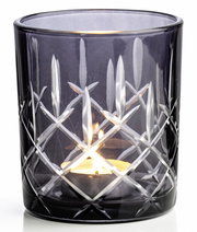 Graues Windlicht mit Schliffmuster, seitliche Perspektive, beleuchtet von einer Kerze.