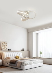 Moderne led-plafondlamp met een gebogen vorm, gezien van onderaf, gemonteerd in een stijlvolle slaapkamer.