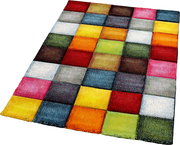 Bunter Patchwork-Teppich mit quadratischen Farbflächen in Rot, Gelb, Orange, Grün, Blau, Grau und Weiß, schräg von oben in leichter Perspektive fotografiert