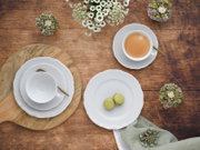 Kaffeeservice 18-tlg aus der Vogelperspektive auf einem Holztisch arrangiert, mit Tassen, Untertassen, Tellern und goldenen Löffeln, umgeben von Blumen und Gebäck.